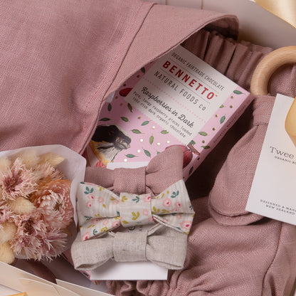 Baby girl gift box in beautiful vintage rose organic linen, including baby girl bloomer and bonnet / sunhat, bow hair ties, natural wooden teether and dried flower posy bouquet. Bennetto Chocolate for new mum.