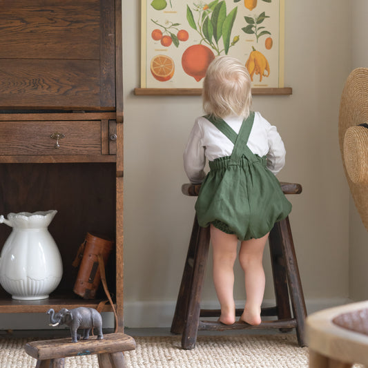 Toddler wearing organic linen romper in forest green by Twee & Co