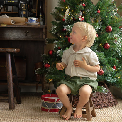 Boy seated wearing organic bloomers, in forest green — made by Twee & Co